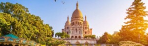 Photo de la Basilique du Sacré-Cœur ensoleillée et vue depuis un jardin en contre bas avec un caroussel