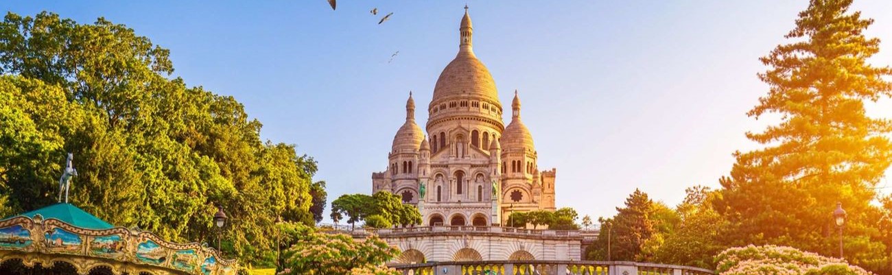 Photo de la Basilique du Sacré-Cœur ensoleillée et vue depuis un jardin en contre bas avec un caroussel