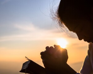 Jeune femme priant dehors avec la bible sur ses genoux