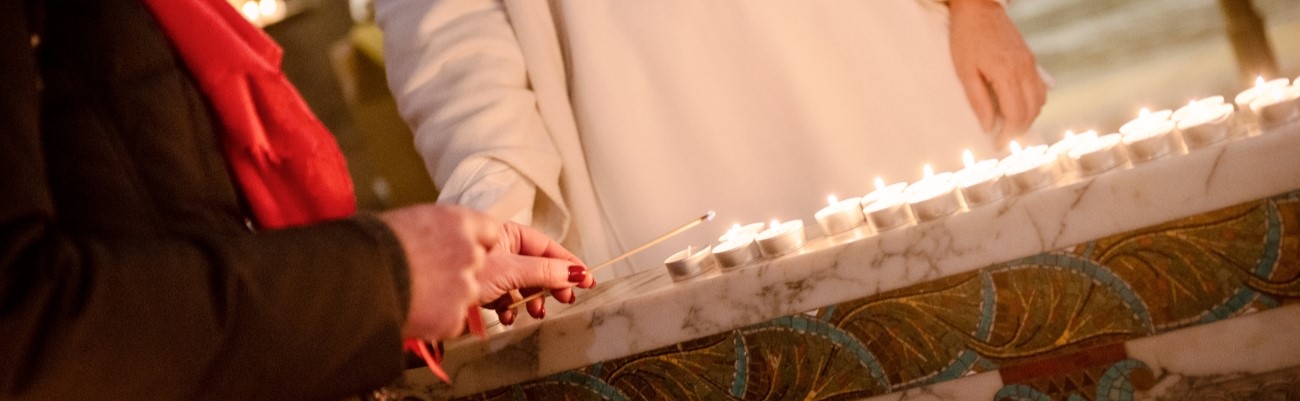 Soeur bénédictine et une femme allumant un cierge